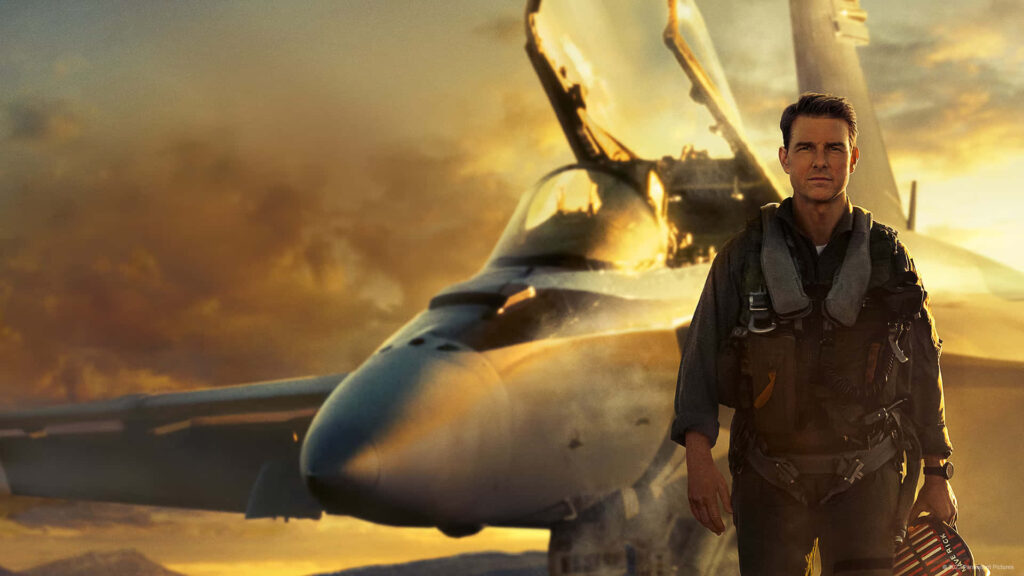 Tom Cruise as Pete Mitchell standing confidently in front of fighter jet Top Gun Maverick wallpaper
