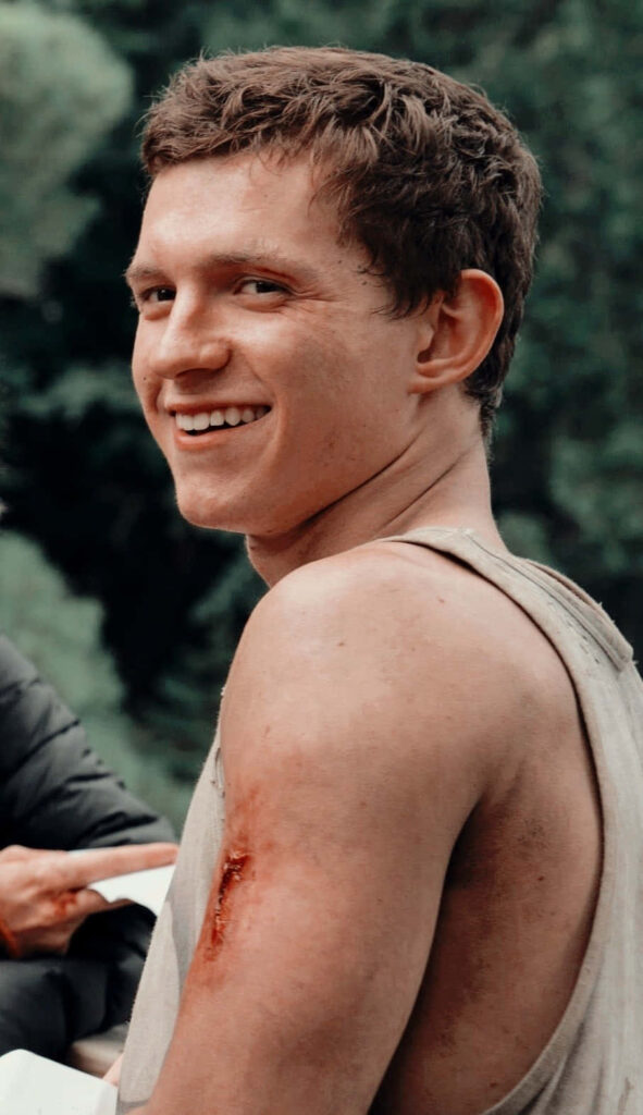 Tom Holland smiling outdoors with natural background casual rugged look vibrant wallpaper background