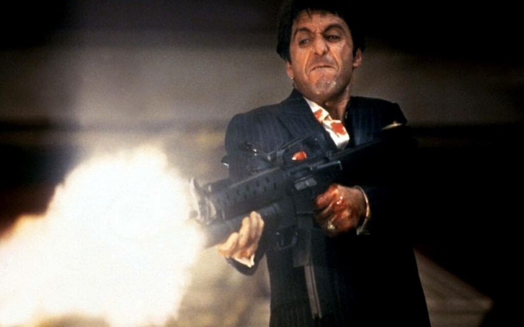 Tony Montana from Scarface firing a machine gun intense action scene wallpaper background