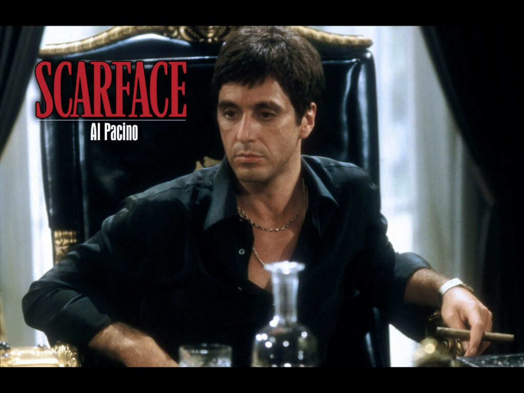 Tony Montana seated confidently in luxurious chair with intense Scarface movie iconic expression Wallpaper