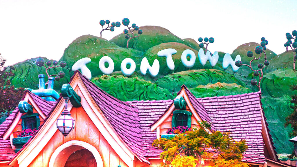 Whimsical Toontown sign on green hills with colorful rooftops Disneyland wallpaper background