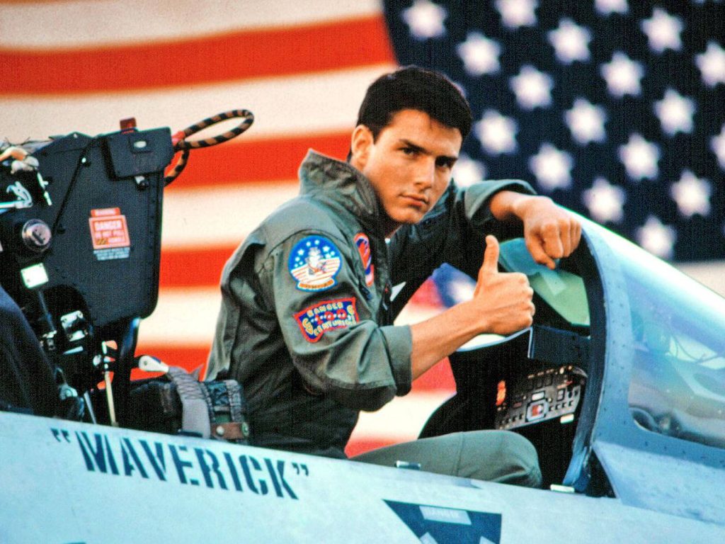 Tom Cruise as Maverick in fighter jet cockpit with American flag Top Gun 80s wallpaper