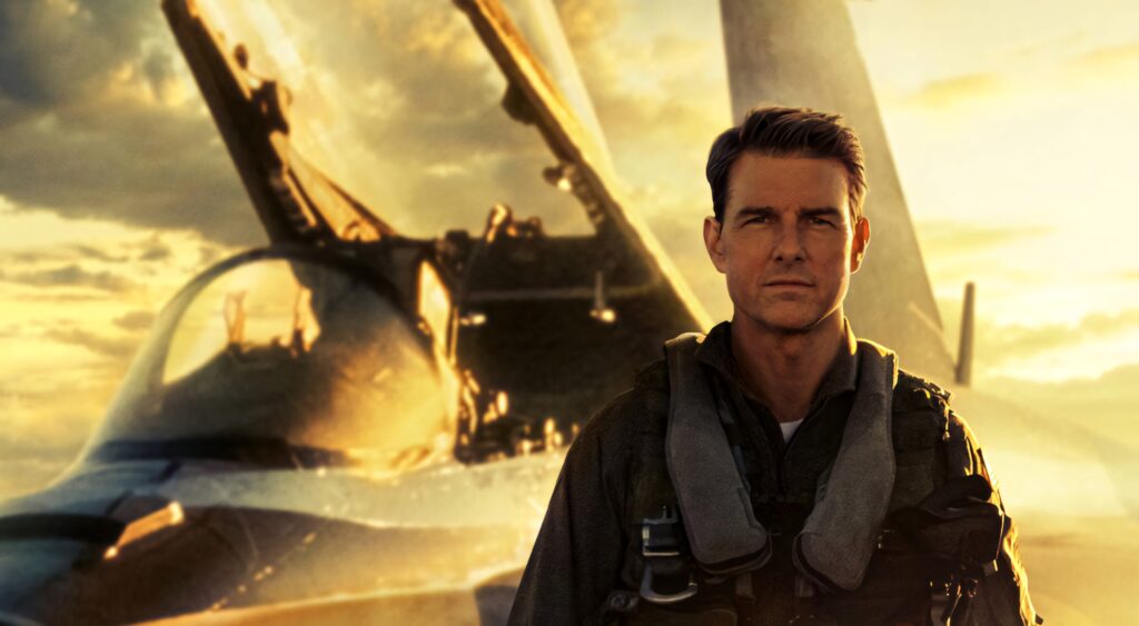 Tom Cruise as Pete Mitchell in flight suit with fighter jet and dramatic sunset Top Gun Maverick Wallpaper