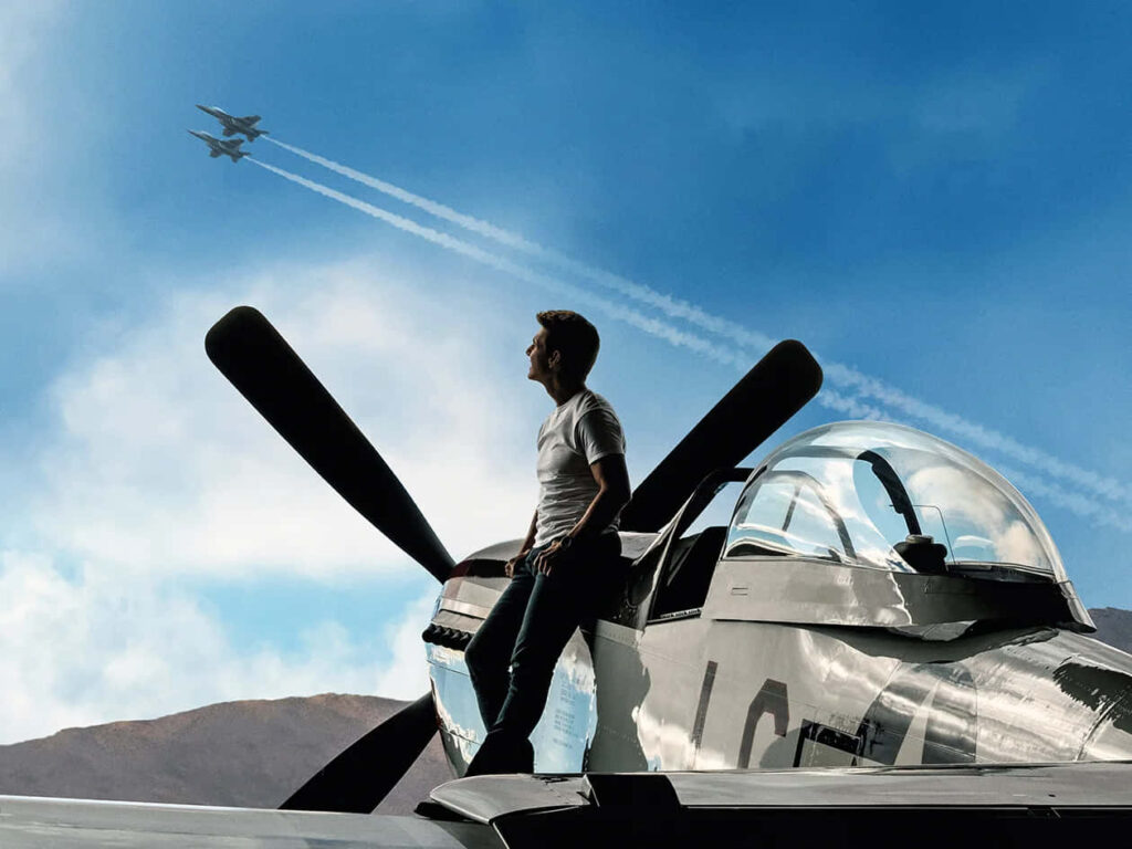 Tom Cruise as Pete Mitchell by fighter jet watching planes Top Gun Maverick wallpaper background