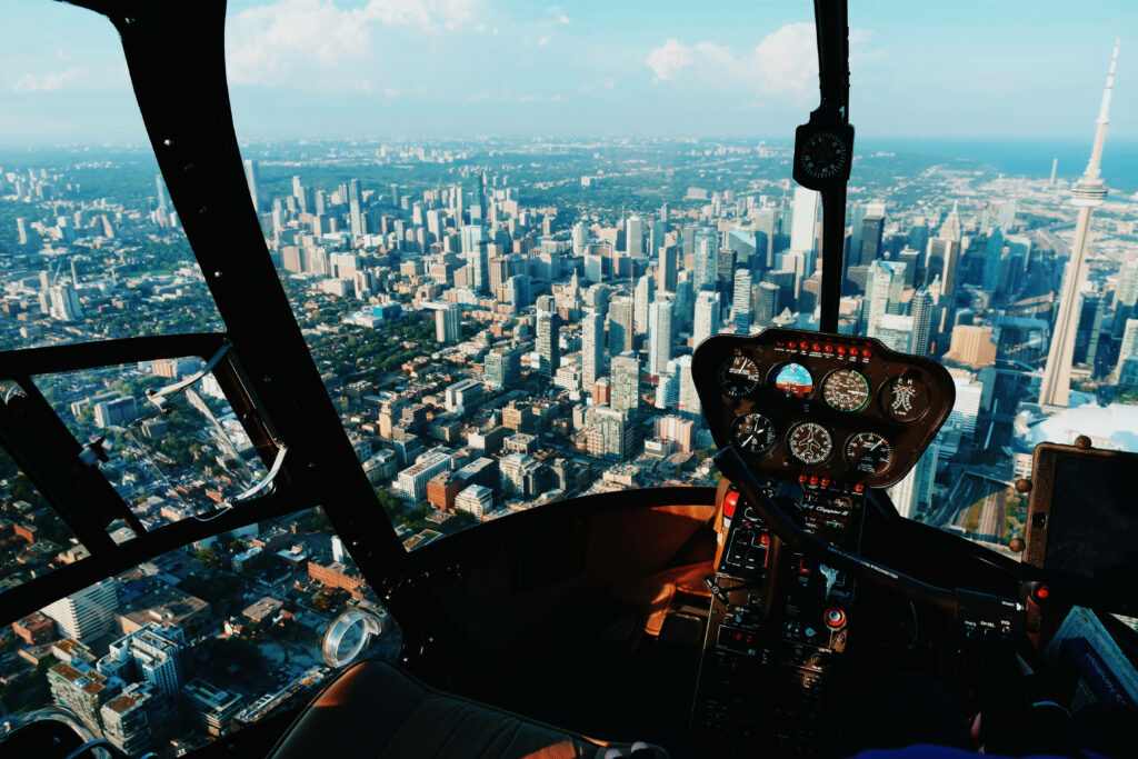Helicopter cockpit view over Toronto cityscape with CN Tower and warm sunlight urban skyline Wallpaper