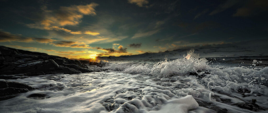 Nature's Majestic Fury: Dramatic Waves Colliding with Shoreline Amidst Twilight Hues Wallpaper