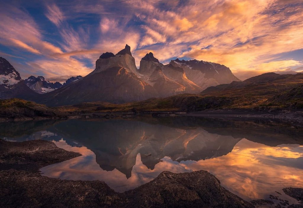 Torres del Paine sunset landscape reflected in lake with warm granite peaks and Patagonia clouds Wallpaper