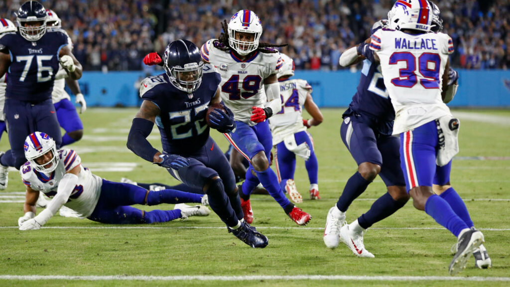 Touchdown Derrick Henry powering through defenders in Titans blue under bright stadium lights Wallpaper