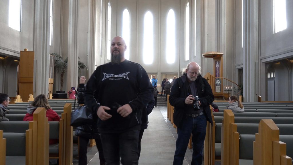 Tourists exploring Hallgrímskirkja church interior in Reykjavík with concrete architecture and windows Wallpaper