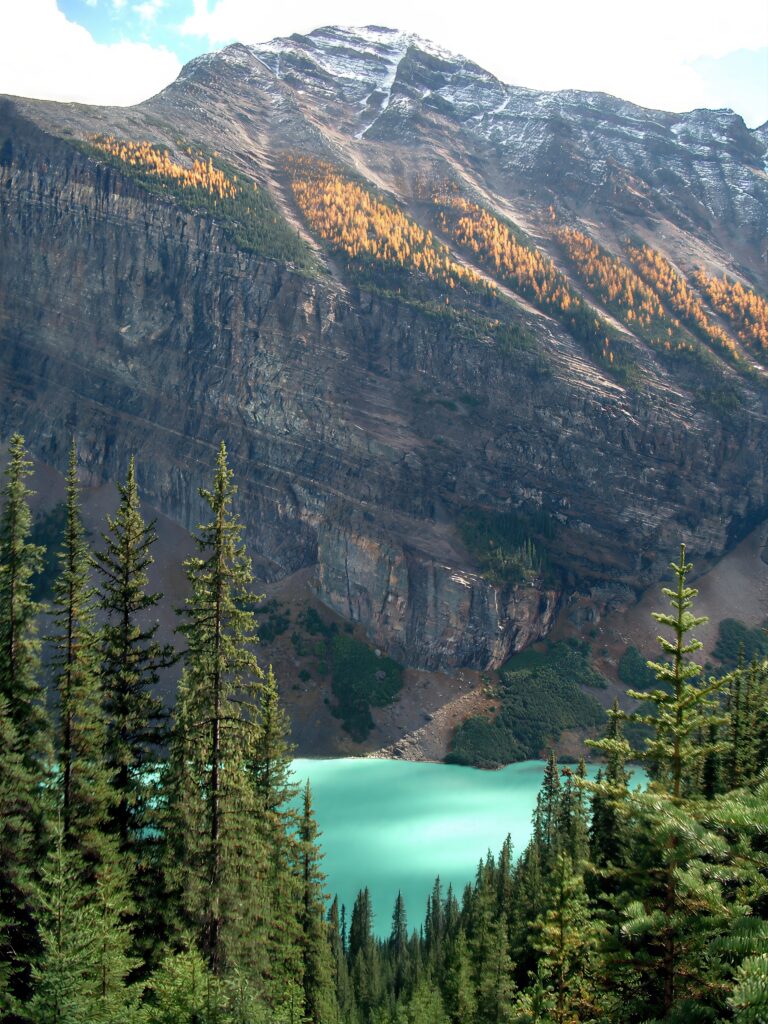 Towering snow-capped mountain above turquoise lake and golden autumn forest landscape wallpaper