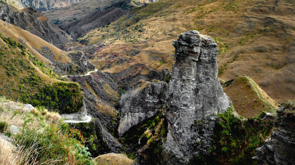 Rugged landscape wallpaper with towering rock formation and winding paths in earthy tones