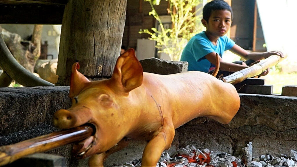 Tradition of Lechon: Roasted Pig Over Fire with Young Helper Wallpaper