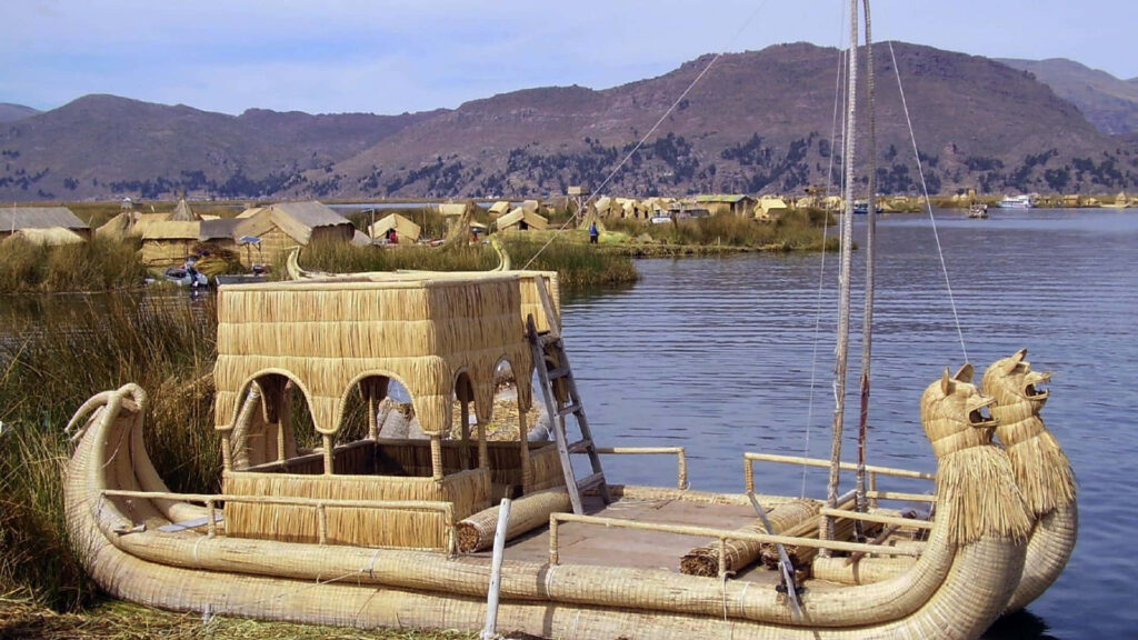 Traditional reed boat on calm Lake Titicaca with mountains and rustic lakeside huts background Wallpaper