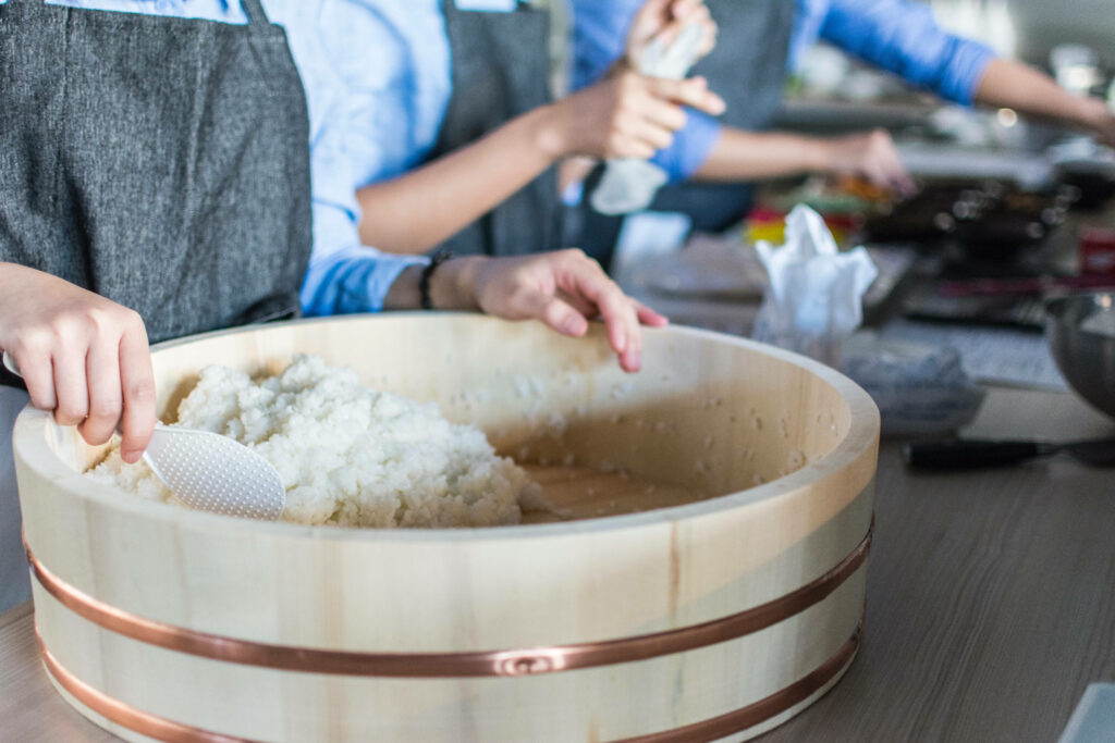 Artisan Sushi Rice Preparation: Apron-Clad Chefs in Wooden Tub Wallpaper