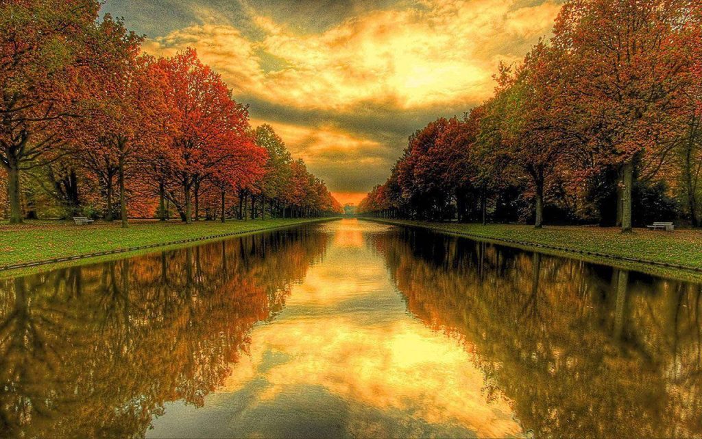 Serene autumn canal with vibrant fall trees and golden sunset reflecting on still water wallpaper