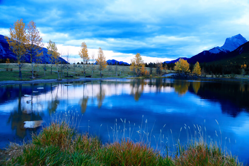 Crystal clear lake reflecting golden autumn trees and mountains under a vivid blue sky wallpaper