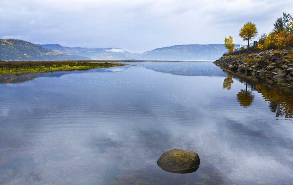 Tranquil lake reflecting mountains autumn trees rocky shore peaceful natural landscape wallpaper background