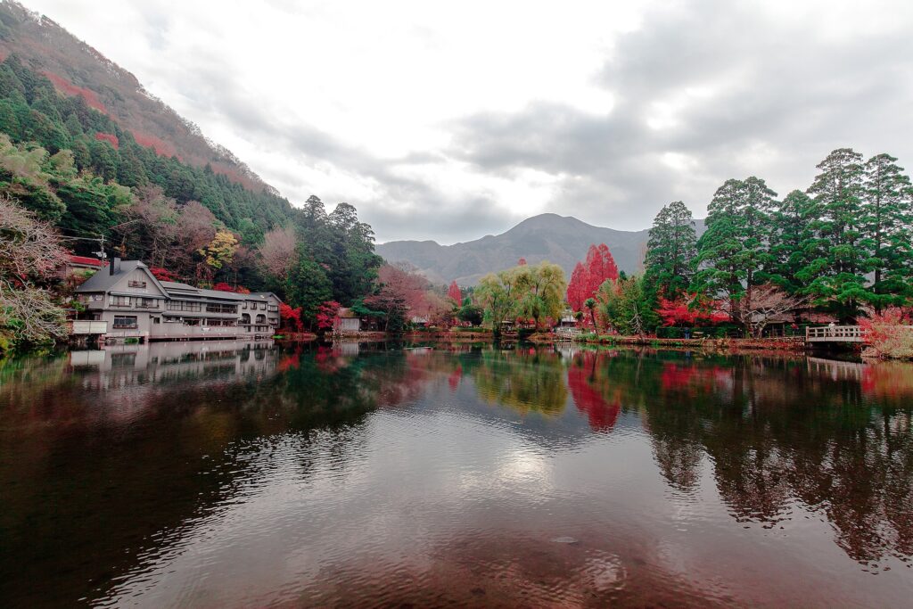 Tranquil autumn lake with colorful trees charming lakeside houses and majestic mountain reflections Wallpaper