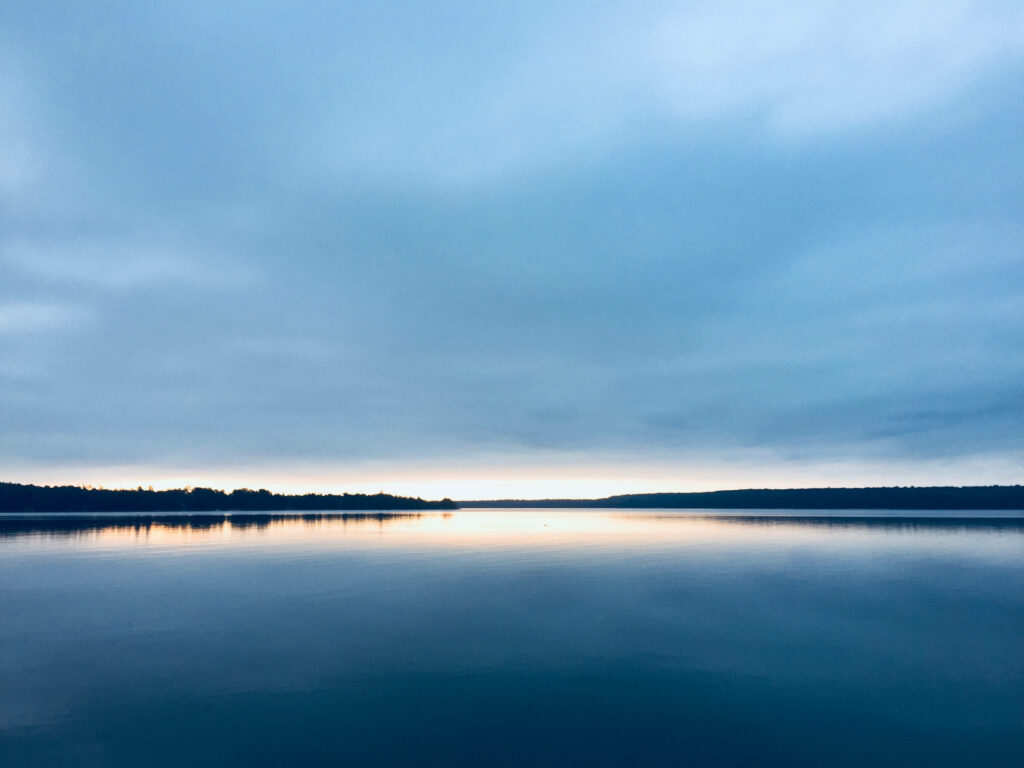 Tranquil Waters: Serene Blue Lake and Sunkissed Horizon Wallpaper
