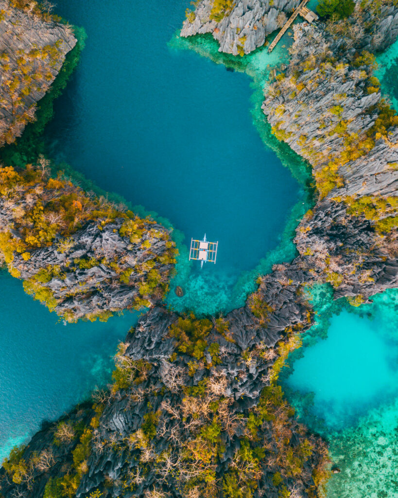 Aerial view of tranquil bay with turquoise waters rugged cliffs lush greenery and small boat Wallpaper