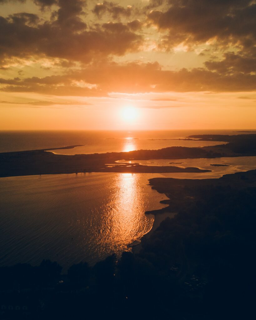 Sunset over tranquil bay with golden reflections calm sea dramatic clouds peaceful dusk wallpaper