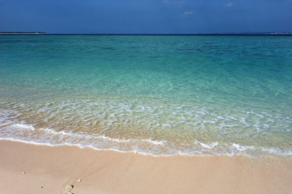 Tranquil beach wallpaper with turquoise water sea foam sandy shore and clear blue sky background