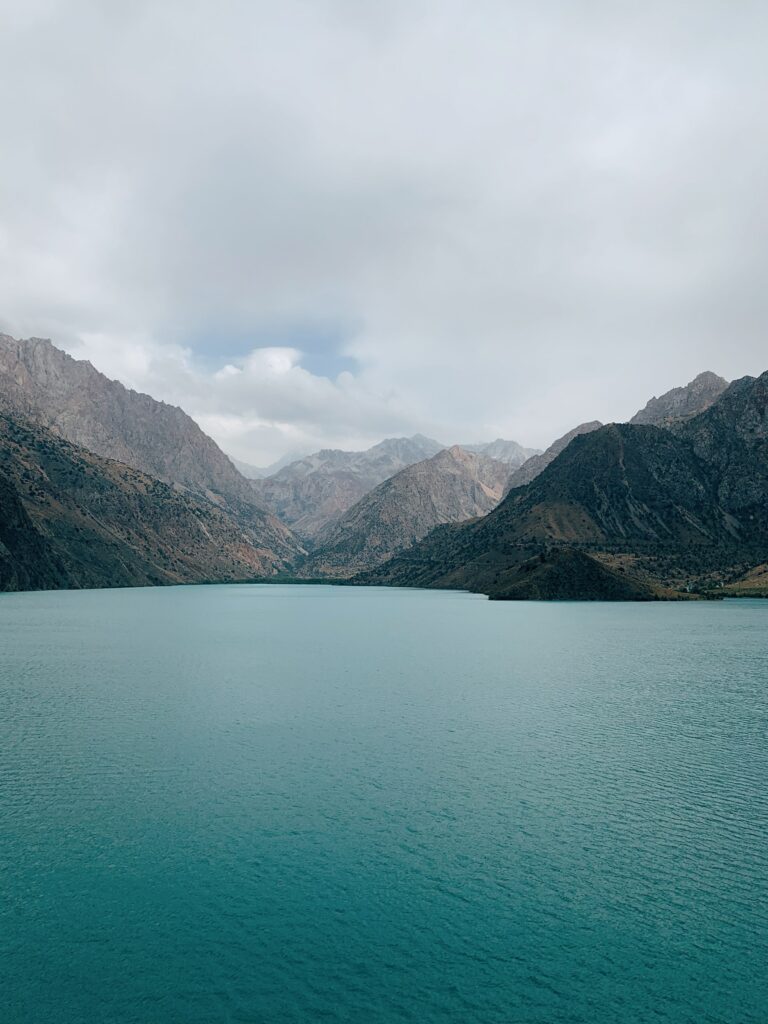 Serene landscape wallpaper with calm blue bay waters and rugged mountain ranges under soft skies