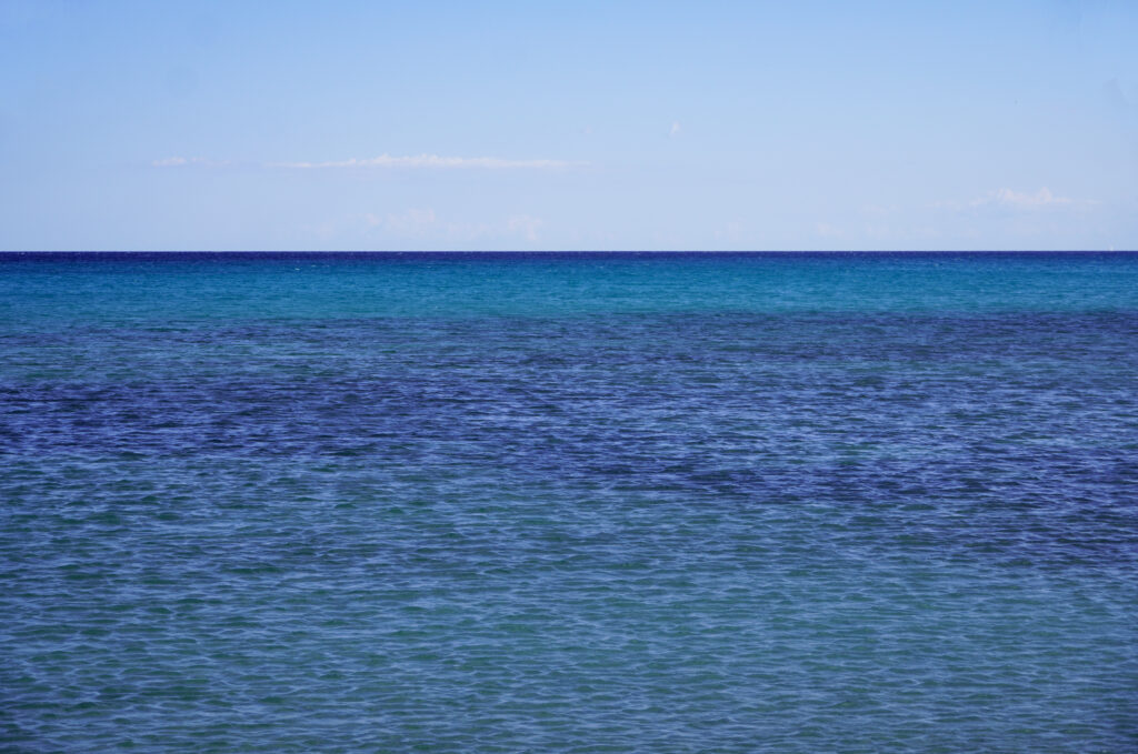 Tranquil sea with gentle ripples under vast blue sky soothing calm ocean wallpaper background
