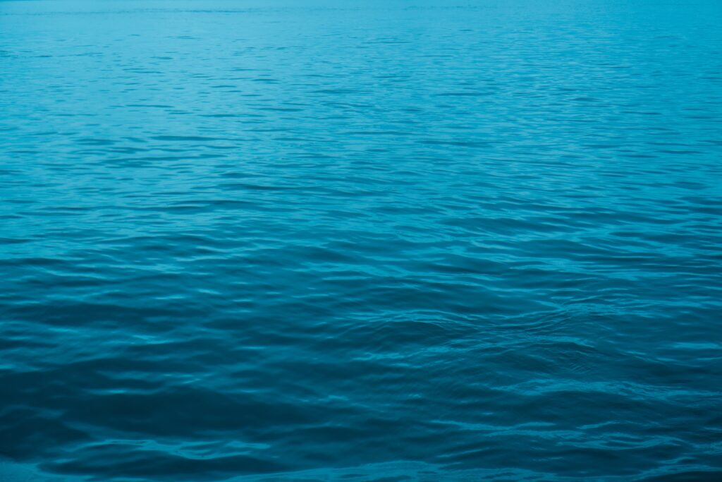 Minimalist wallpaper of tranquil blue sea with gentle rippling waves creating serene calm background