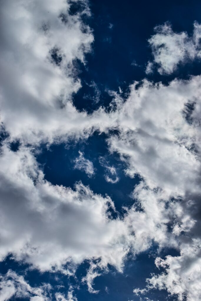 Vibrant blue sky with soft white clouds creating a tranquil and airy wallpaper background