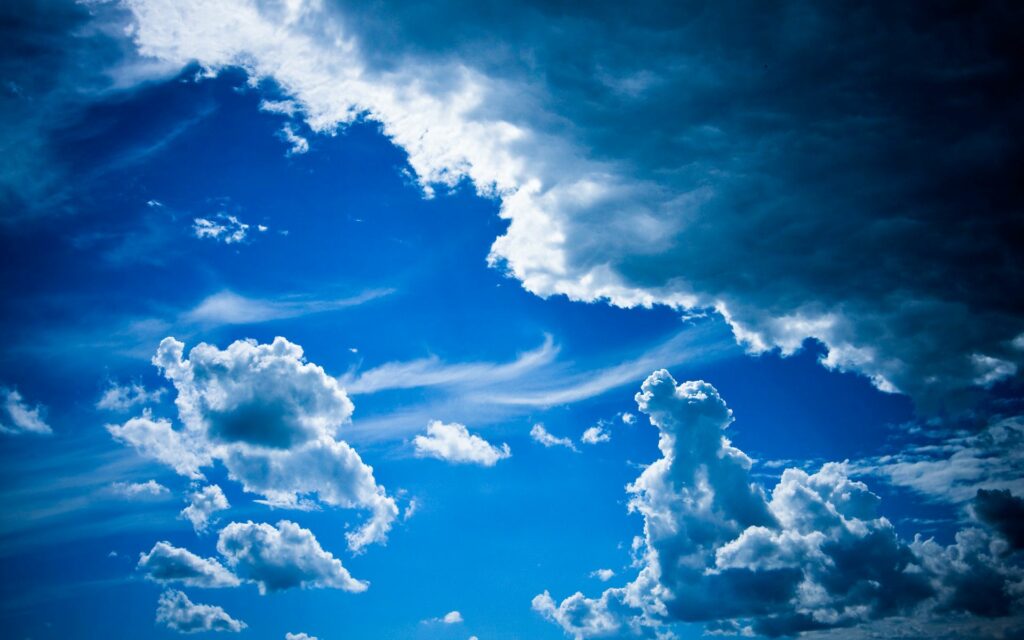 Vibrant blue sky with voluminous white clouds showcasing dynamic patterns and tranquility Wallpaper