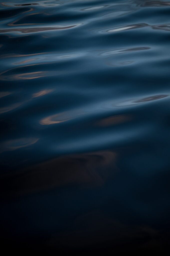 Calm deep blue water waves with subtle reflections serene minimalist nature wallpaper background