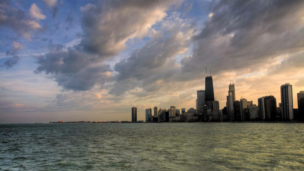 Calm ocean with Chicago skyline at sunset under dramatic cloudy sky urban landscape wallpaper