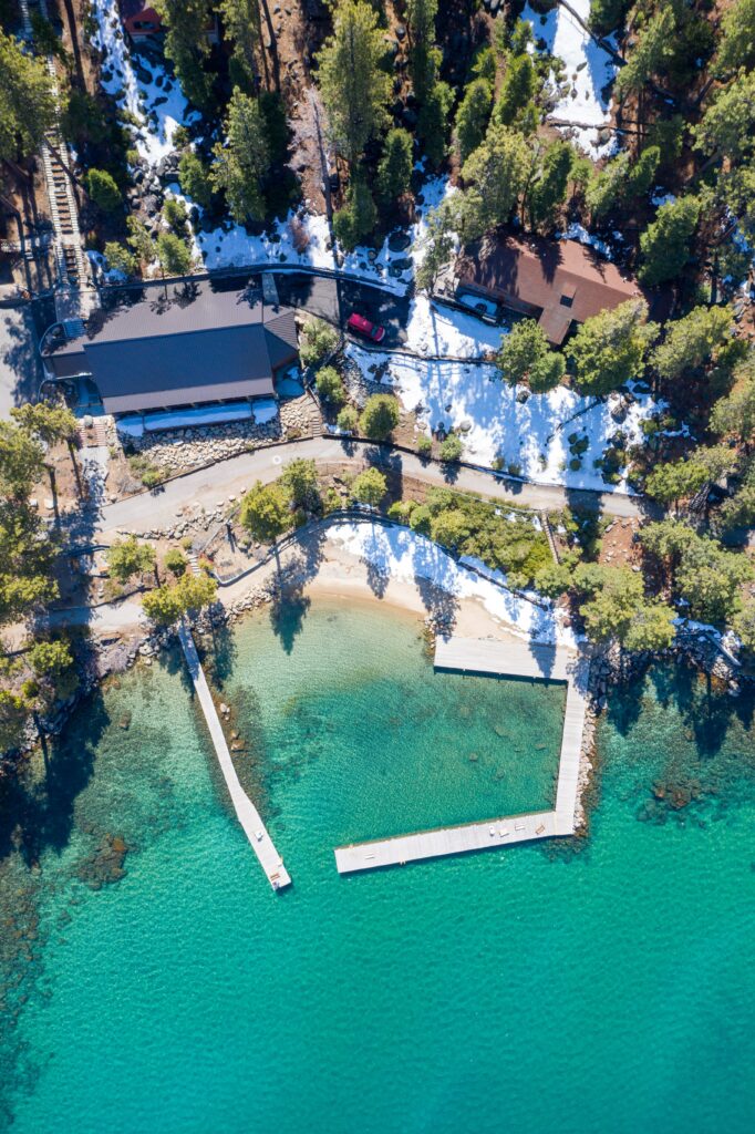 Aerial view of turquoise sea sandy beach docks and modern buildings among pine trees coastal wallpaper