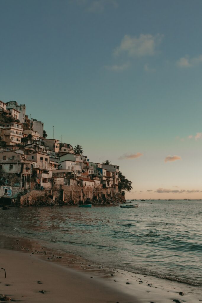 Serene coastal wallpaper with rustic cliffside buildings boats and warm light reflecting on sea