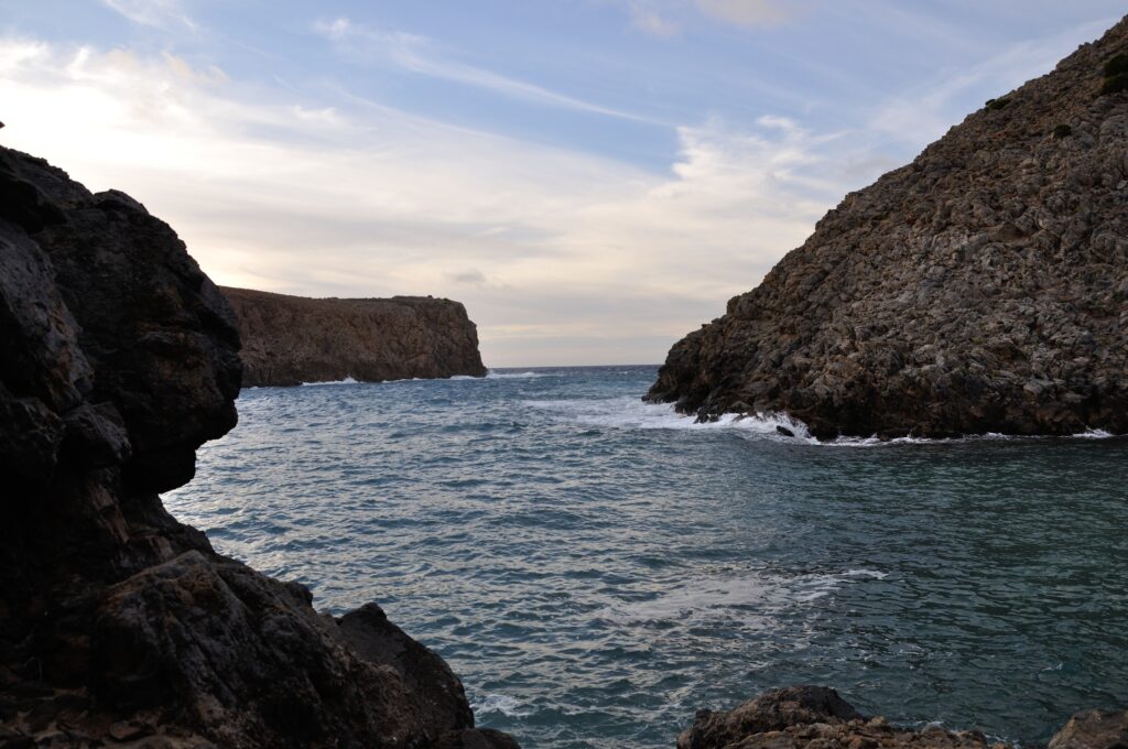 Rugged rocky cliffs framing calm sea waves under a soft cloudy sky coastal nature wallpaper