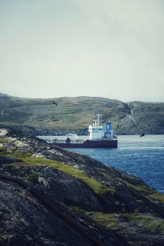 Large ship sailing calm blue sea near rocky coastline with distant birds serene maritime landscape Wallpaper