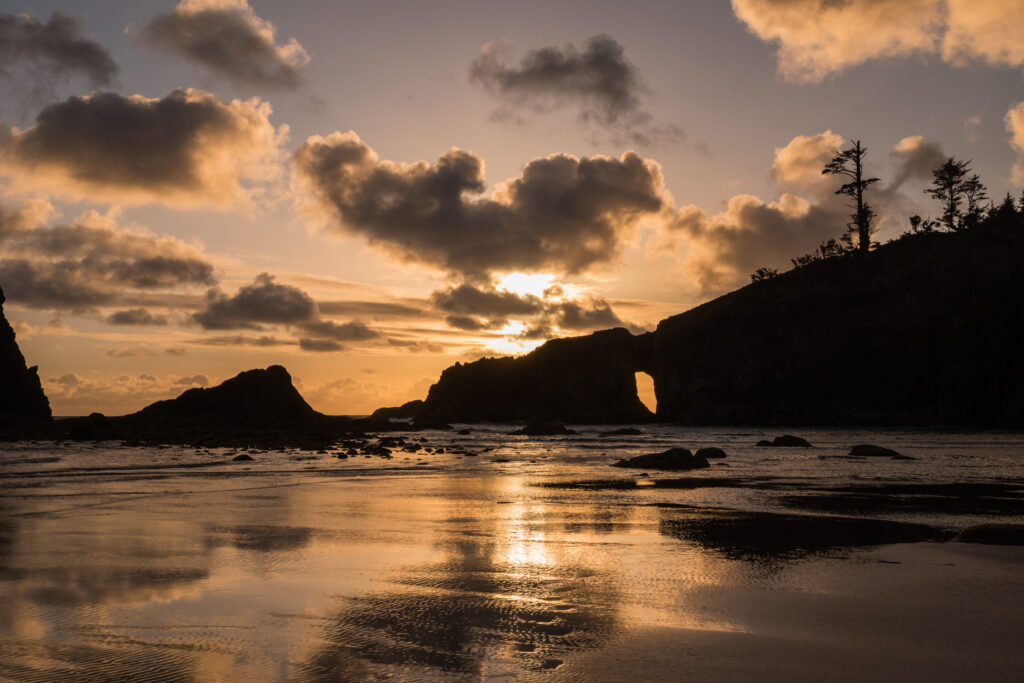 Tranquil coastal sunset with dramatic clouds rugged rocks calm sea reflecting golden hues wallpaper