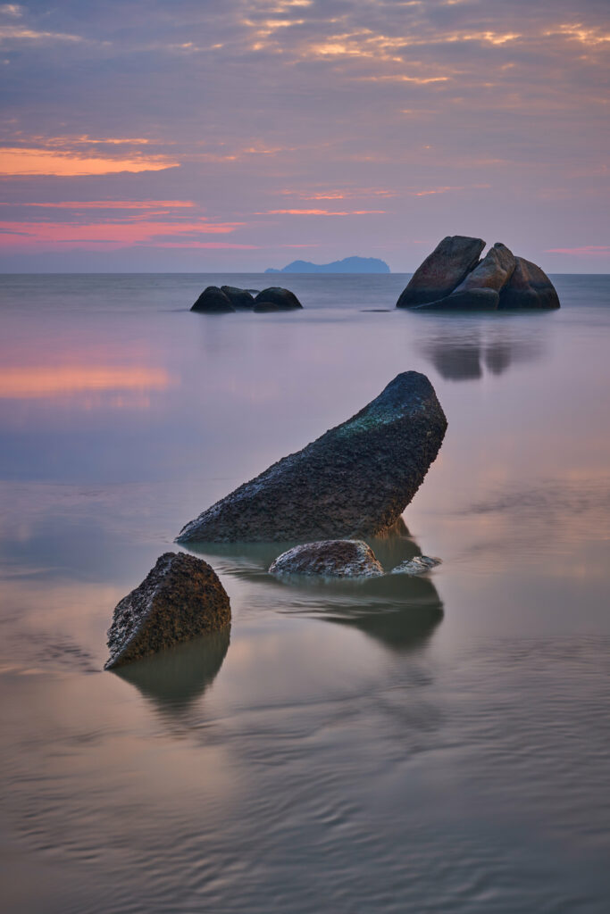 Serene coastal wallpaper with smooth rocks calm sea pastel sky soft clouds tranquil horizon