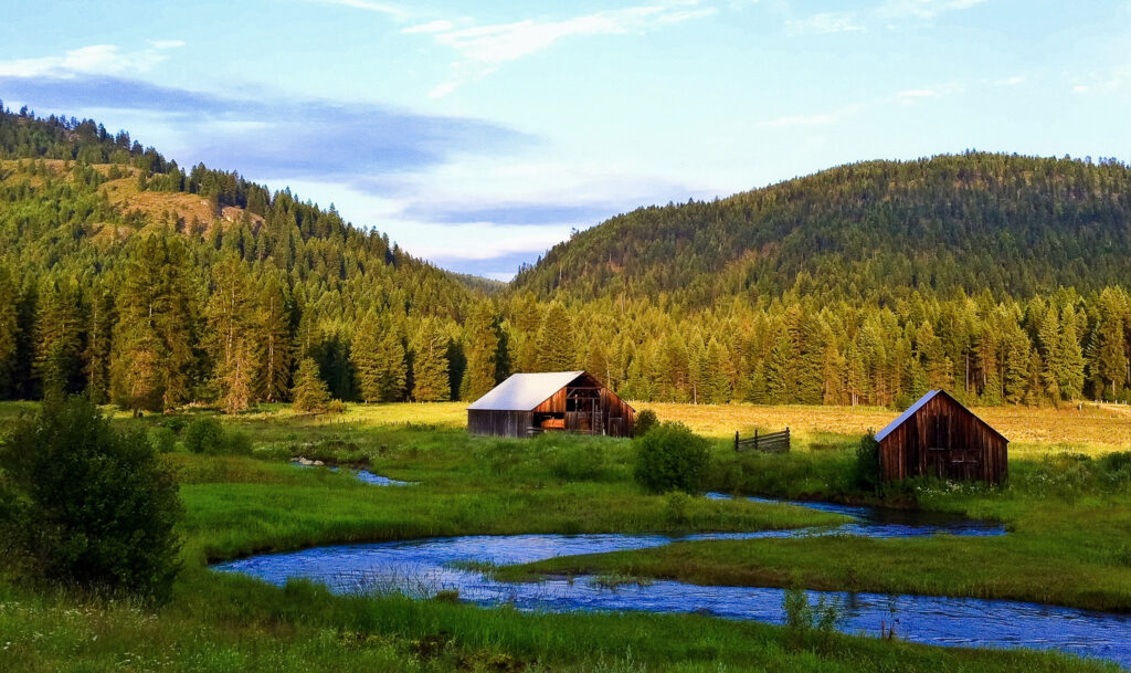 Serene countryside landscape with river pine trees wooden barns rolling mountains vibrant sky wallpaper