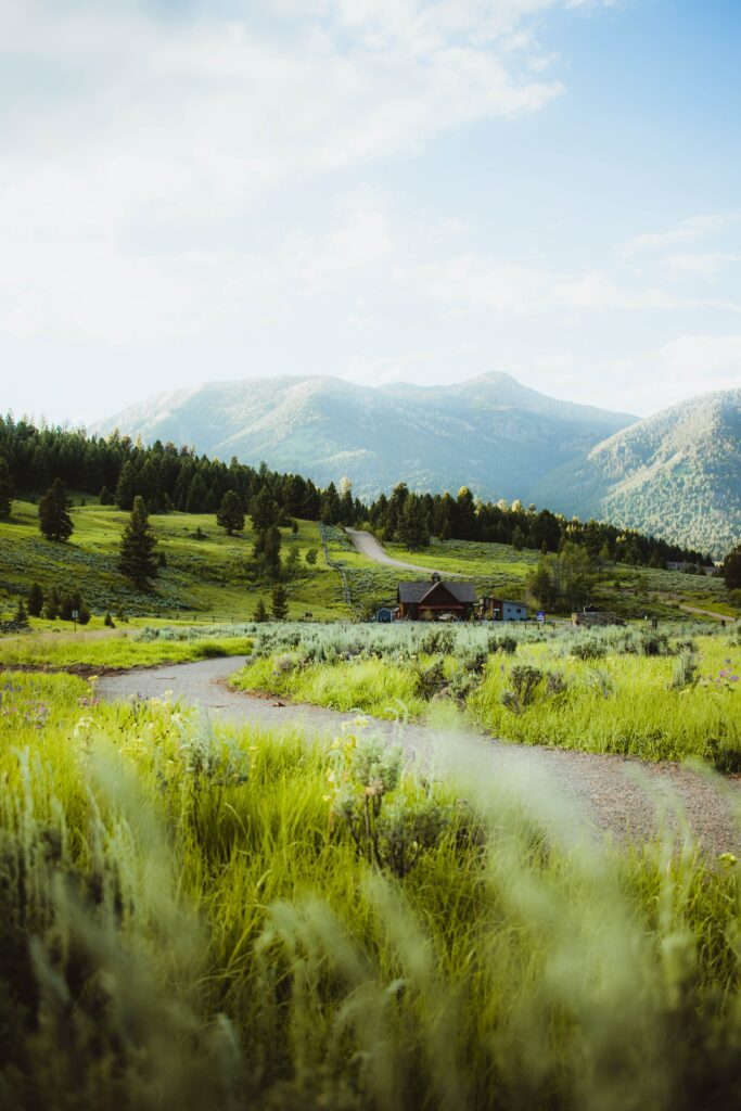 Peaceful countryside wallpaper with hilltop cottage lush grass winding paths and mountain backdrop