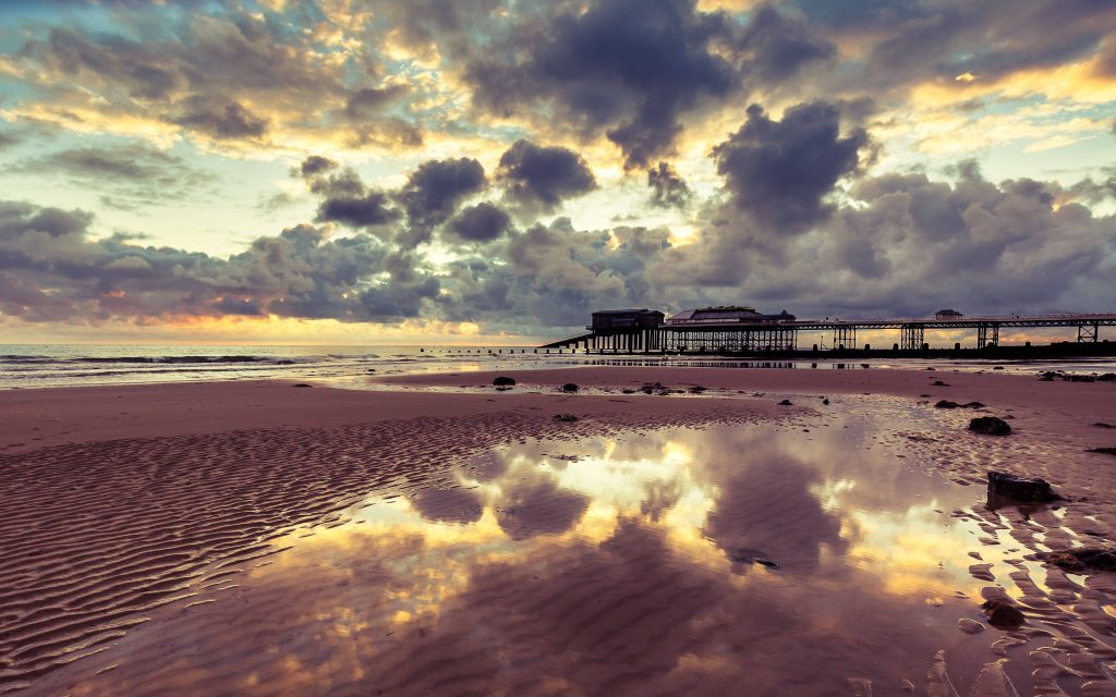Cromer Pier at sunset with golden clouds reflected on wet beach sand serene landscape wallpaper