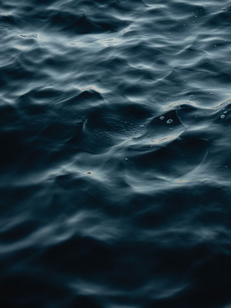 Tranquil deep blue waves on dark water with reflective surface wallpaper background