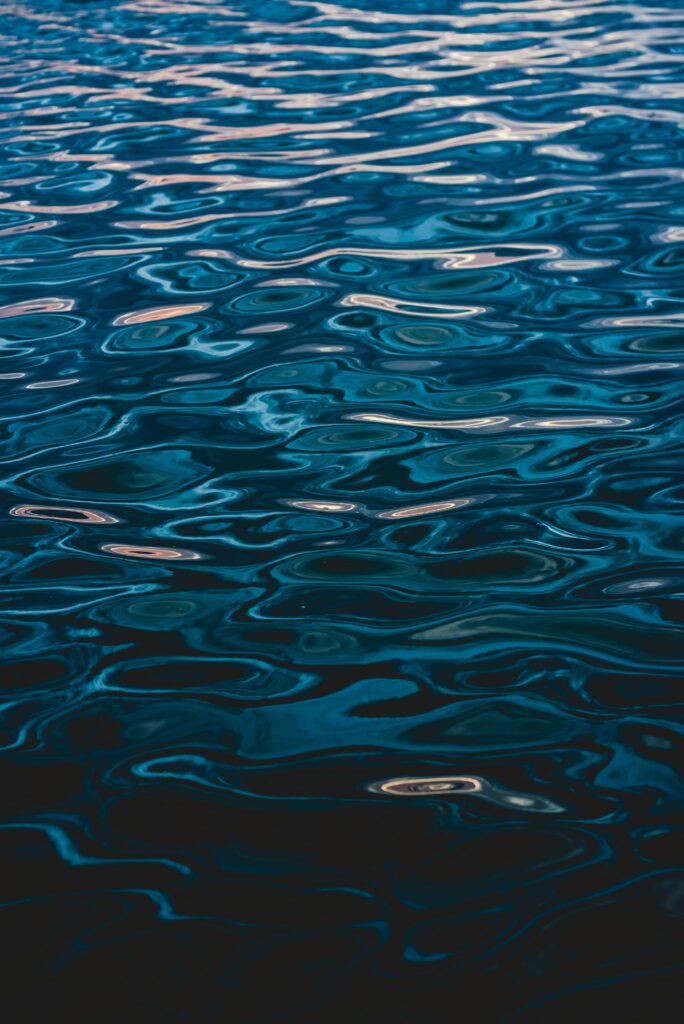 Calm deep blue sea surface with gentle ripples and flowing circular wave patterns wallpaper background