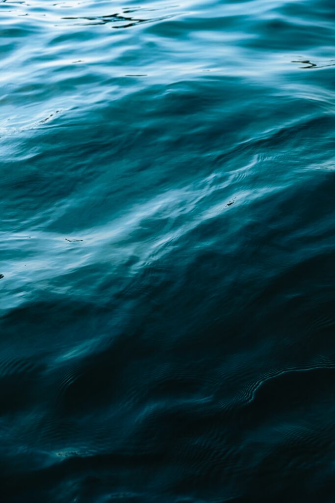 Close-up of deep blue ocean water with gentle waves and natural light glare wallpaper background
