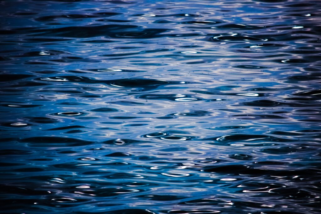 Calm deep blue sea water surface with gentle ripples and reflections abstract wallpaper background