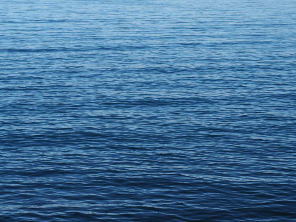 Tranquil deep blue water with gentle ripples and waves serene minimalist wallpaper background