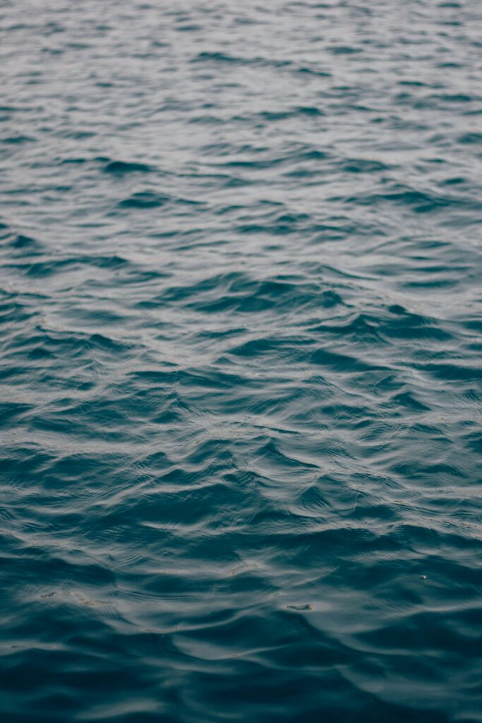 Tranquil deep blue water wallpaper with gentle waves and soft ripples creating calm serenity