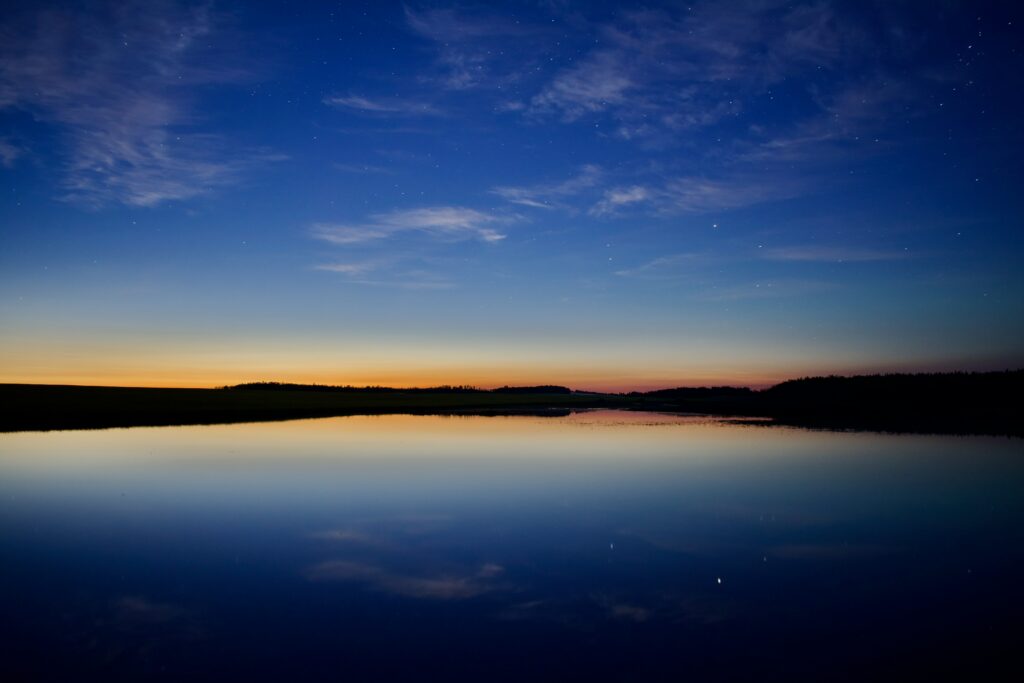 Tranquil dusk horizon wallpaper with calm river reflecting deep blue sky and golden sunset