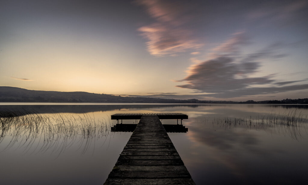 Tranquil pier over calm evening water with pastel sky and gentle clouds for peaceful relaxation Wallpaper